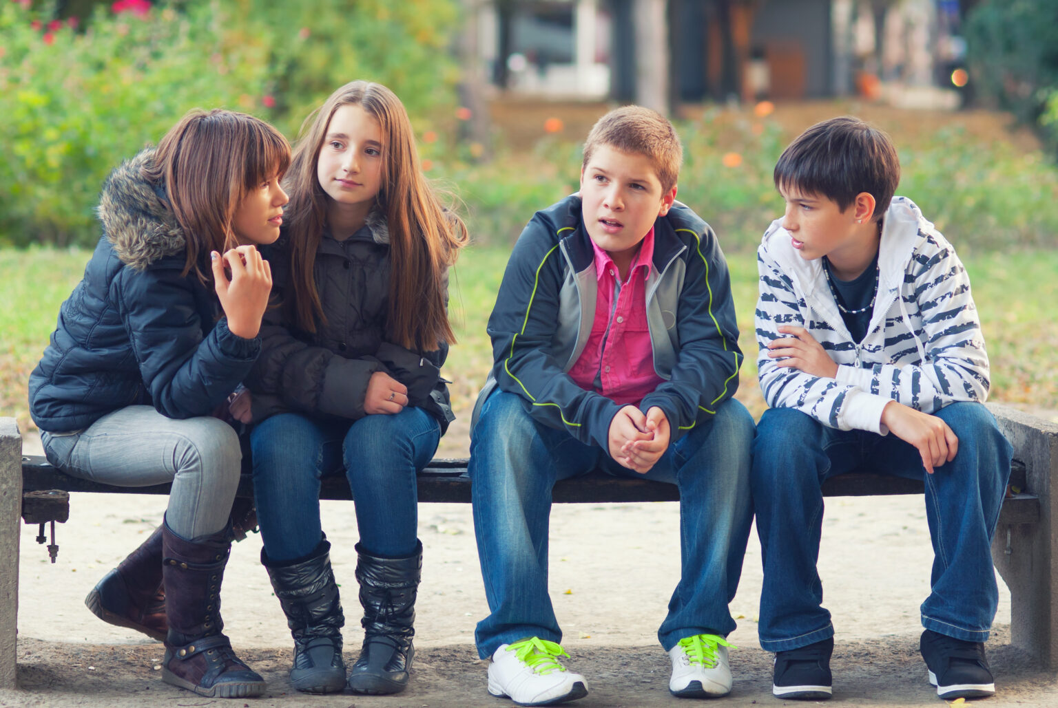 A group of young people sitting on a bench talking