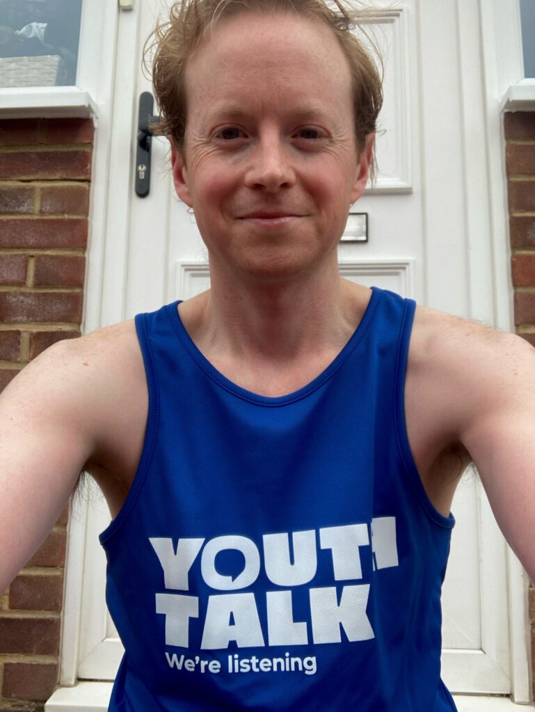 Participant of the London Marathon smiling in a Youth Talk vest