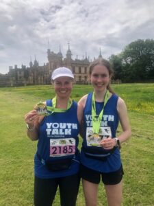 Two Herts Half Marathon finishers holding their medals