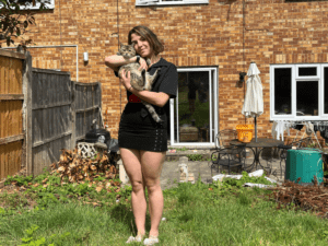 Emily holding her tabby cat, Tilly, and smiling